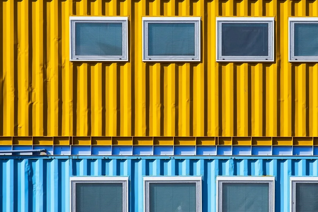 Dos módulos de contenedor apilados, uno amarillo y otro azul, con ventanas de marco blanco