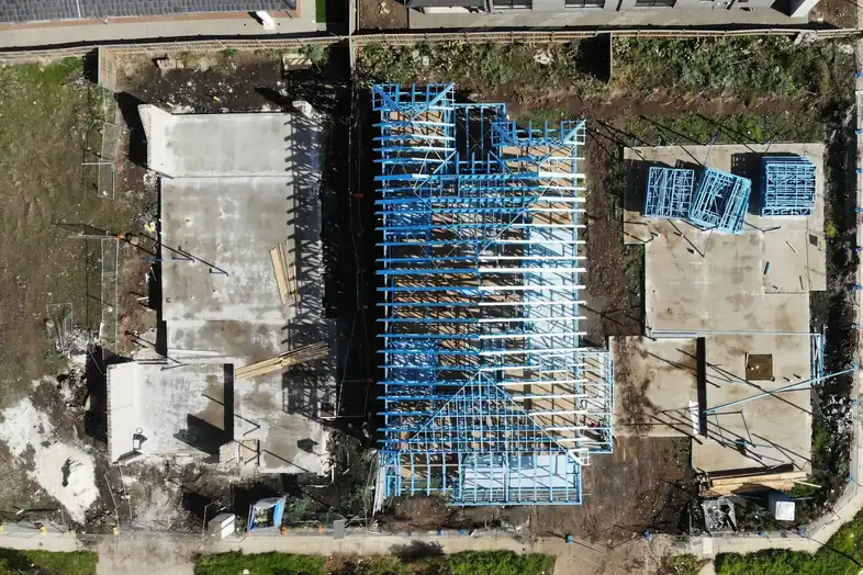 Vista aérea de una vivienda en obra, con su estructura de acero azul levantada sobre el terreno