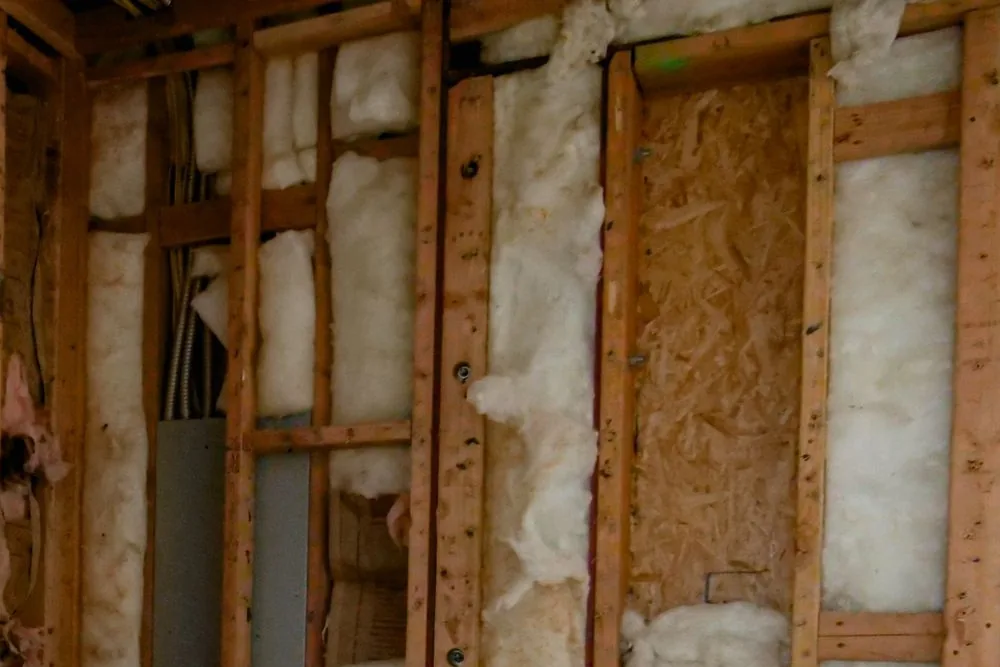 Pared de una vivienda en obra con aislante de lana entre los montantes de madera