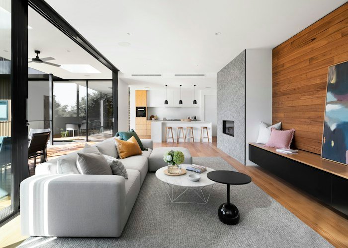 Salón luminoso de vivienda modular con grandes ventanales y suelo de madera